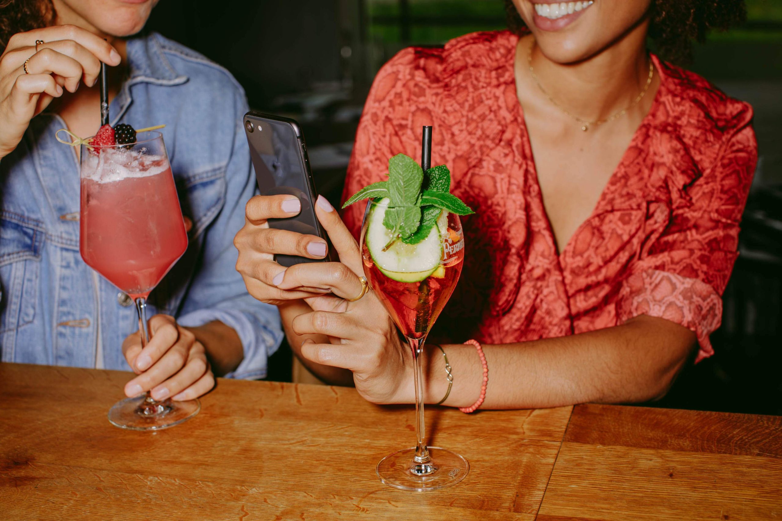 la imagen muestra a dos comensales disfrutando de una bebida Uno de los comensales está tomando una foto de sus bebidas con su teléfono celular.