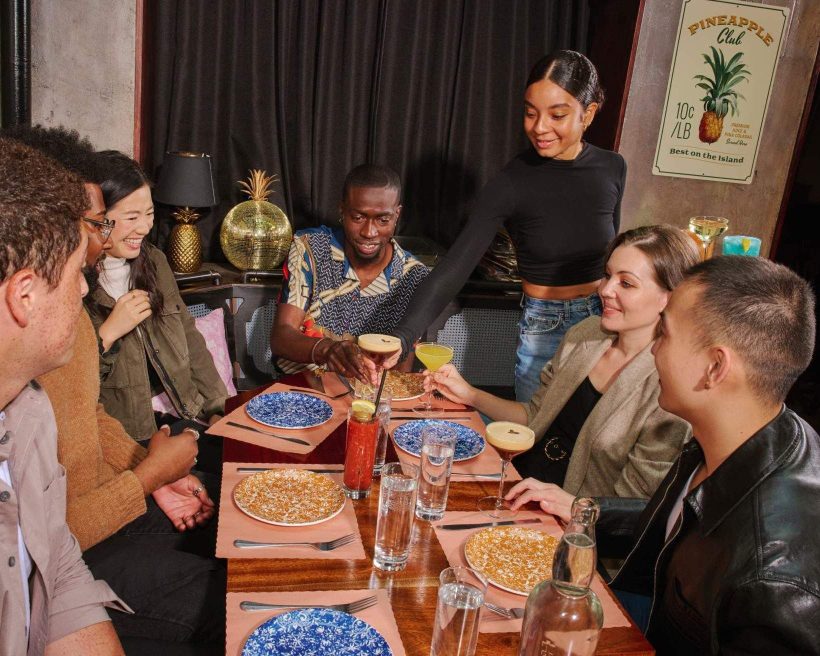 La imagen muestra a un grupo de comensales disfrutando de una comida en un restaurante.
